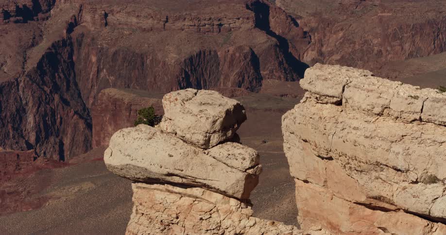 Rock formations near the edge of a canyon and mountains in the distance