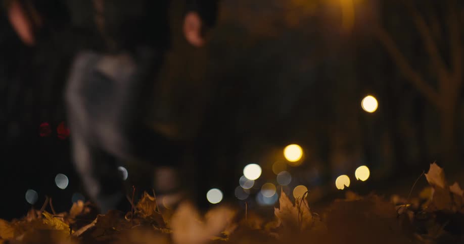 A woman starts running as she realizes a man is following her down a sidewalk at night