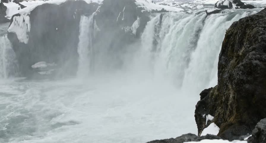 A waterfall is pouring down with mist rising in the air