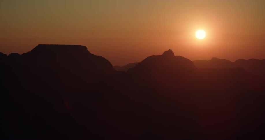 The sun is setting in the horizon of mountains