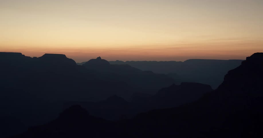 Silhouettes of mountains in a hazy orange sky