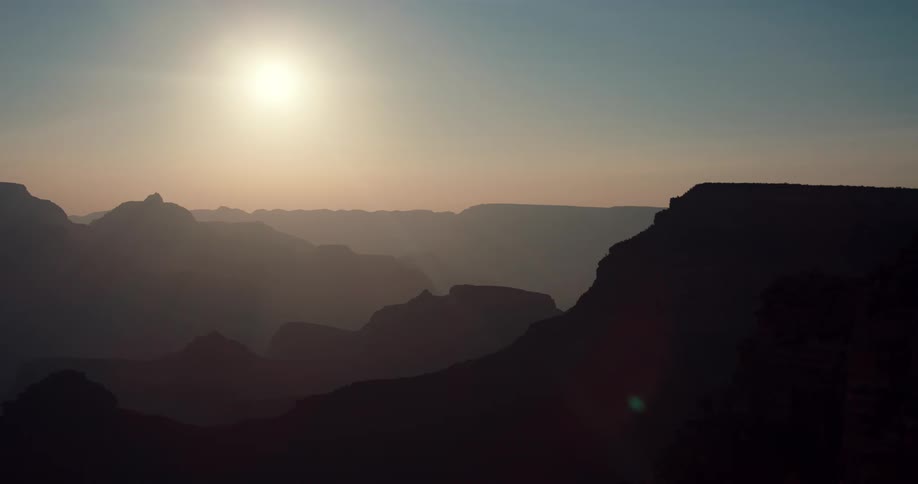Aerial view of the sun setting above the mountains is displayed