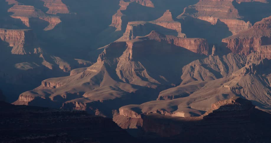The sun shines brightly upon rock formations and mountains