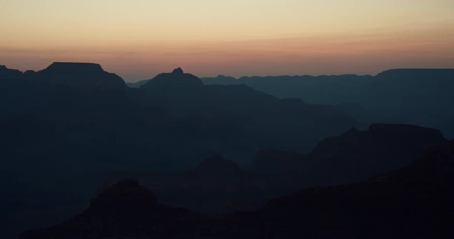 Silhouettes of mountains in a hazy orange sky