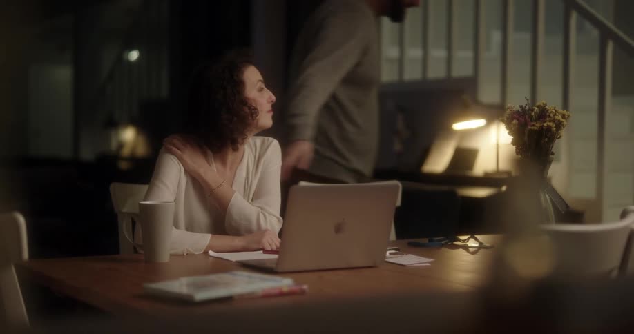 A man gives a drink to a woman working on her computer