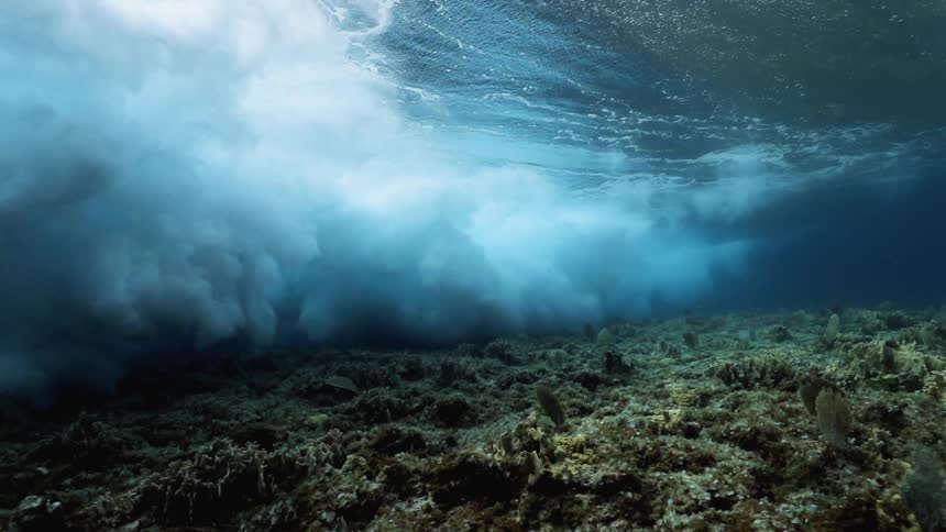 Underwater footage of the ocean floor and waves above