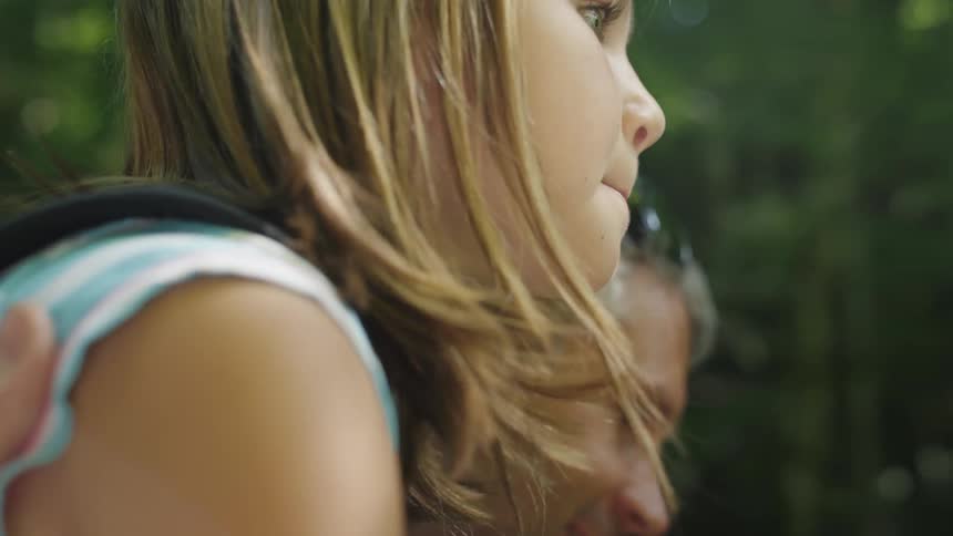 A girl and her father rest during a hike in the woods