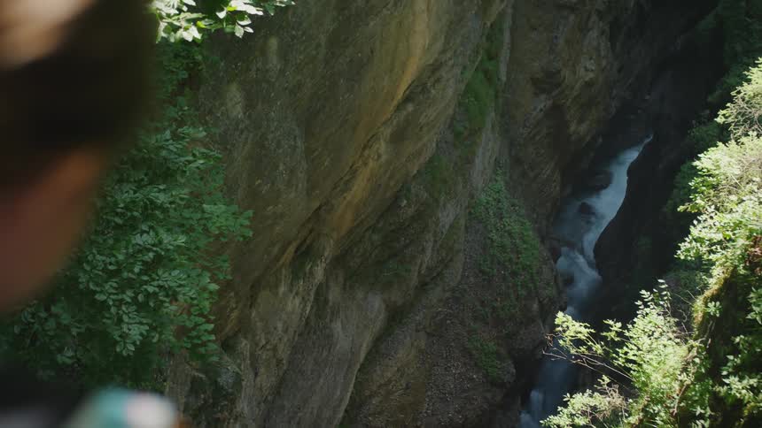 Young girl looking at a river at the bottom of a ravine in the mountains