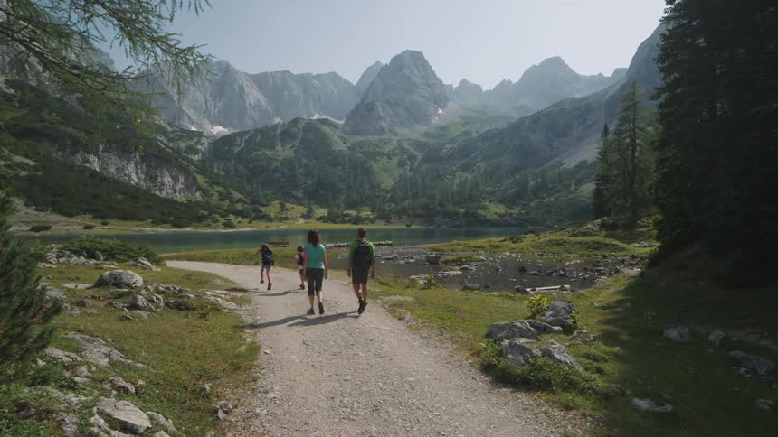 A family walks together on a trail past a lake in a canyon