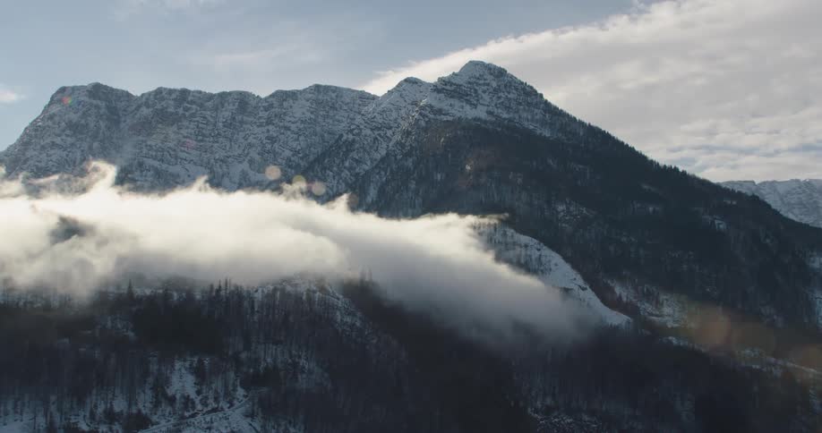 Snow covered forested mountains high among the clouds