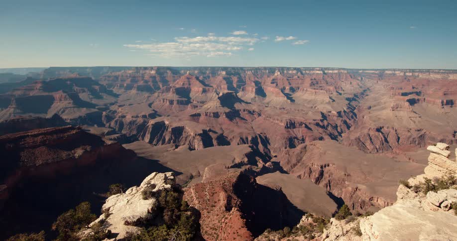 The sun is shining brightly upon mountains and rock formations in the badlands