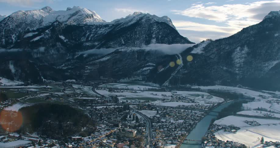 A dense neighborhood sits along a river below a mountain range