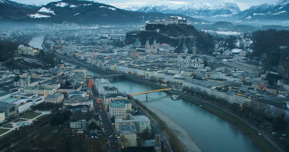 Aerial view of a river flowing through a city covred in fog in the mountains