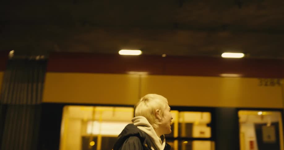 Sad fearful young blonde woman walking on the city street at night