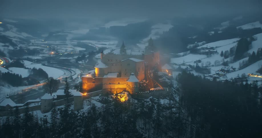 A large building on top of a hill with a small town in the valley below