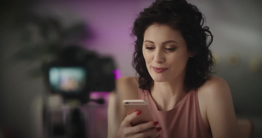 A woman uses her cell phone while filming herself
