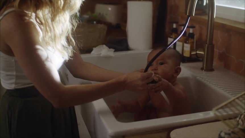 A mother is giving her newborn a bath