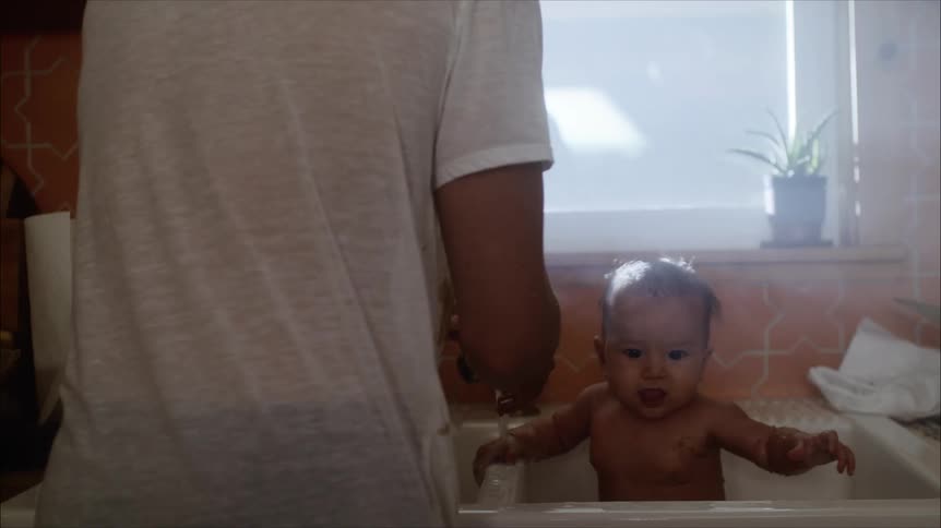 A father bathing a baby in a sink