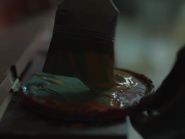 A person putting paint on a paintbrush