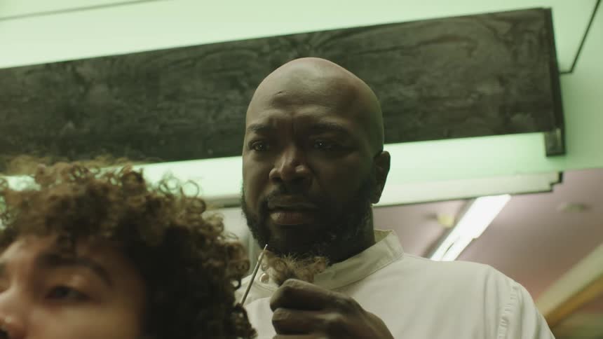 A barber cutting a clients hair in a room