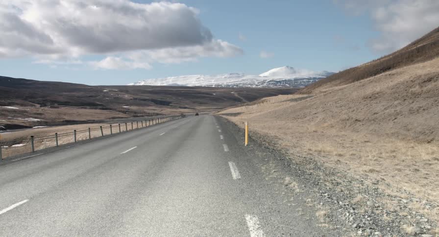 Cars drive over a long stretch of desert road