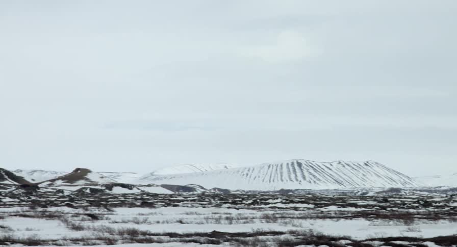 A field leads to mountains all covered with snow
