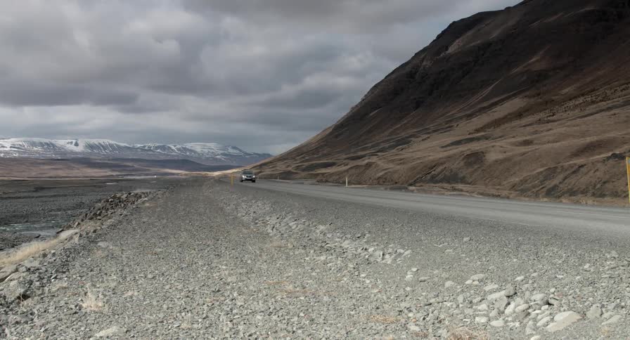 Car traveling a road in a barren area on a cloudy day
