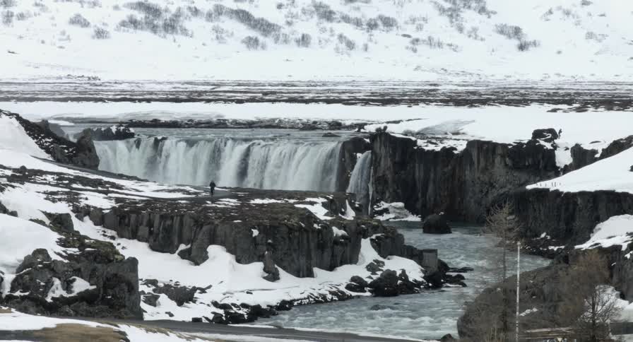 Person walking next to a waterfall in a wintry wonderland