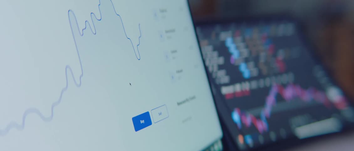 Cryptocurrency graphs on a laptop screen near a tablet scrolling up and down
