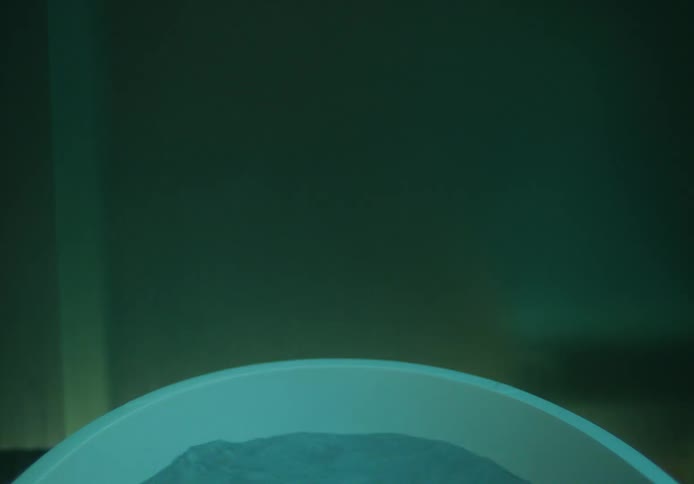 A young woman in a tub leans back and sinks under the water