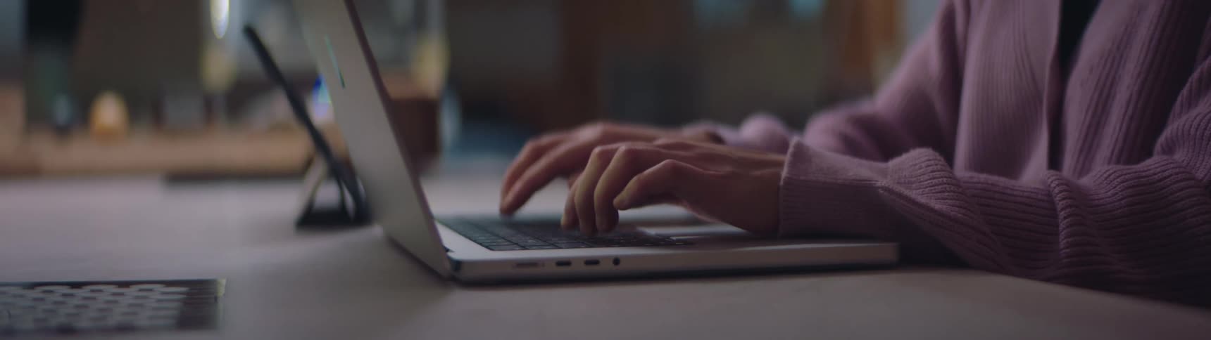 A woman is sitting at a table in an office and typing on a laptop in the daytime