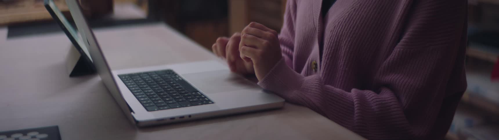 Someone is sitting at a desk typing on a laptop computer