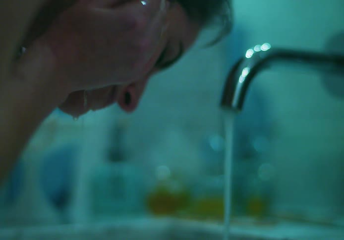 A woman washing her face at a bathroom sink