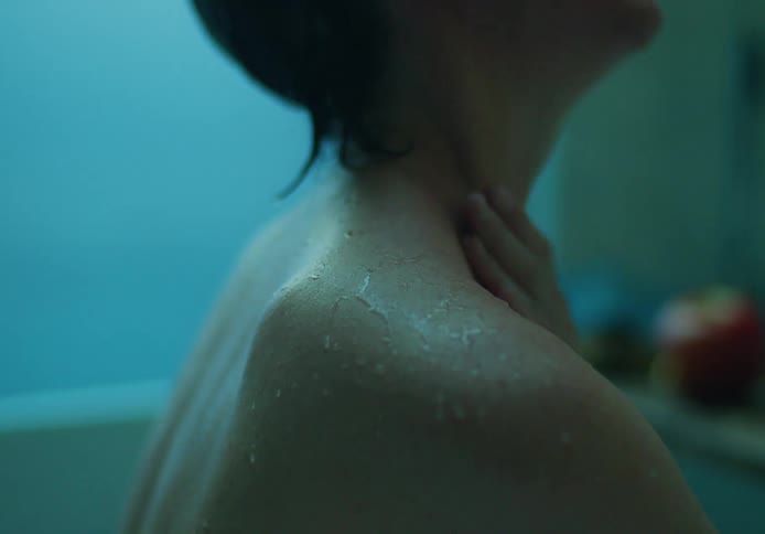 Nude woman washes herself with water using her hand