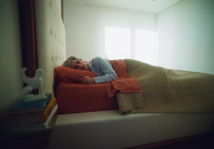 Woman is sleeping on a bed in a during the daytime