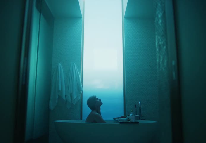 Man bathes in tub lit by blue tinted lighting
