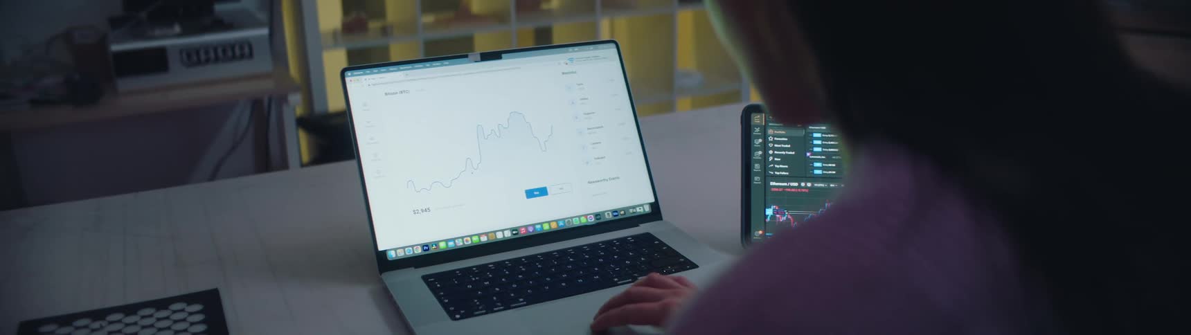 A woman looking at graphs and numbers on a laptop screen