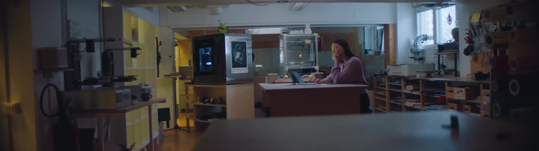 A woman is sitting at a desk working at a laptop during the daytime at work in a design studio