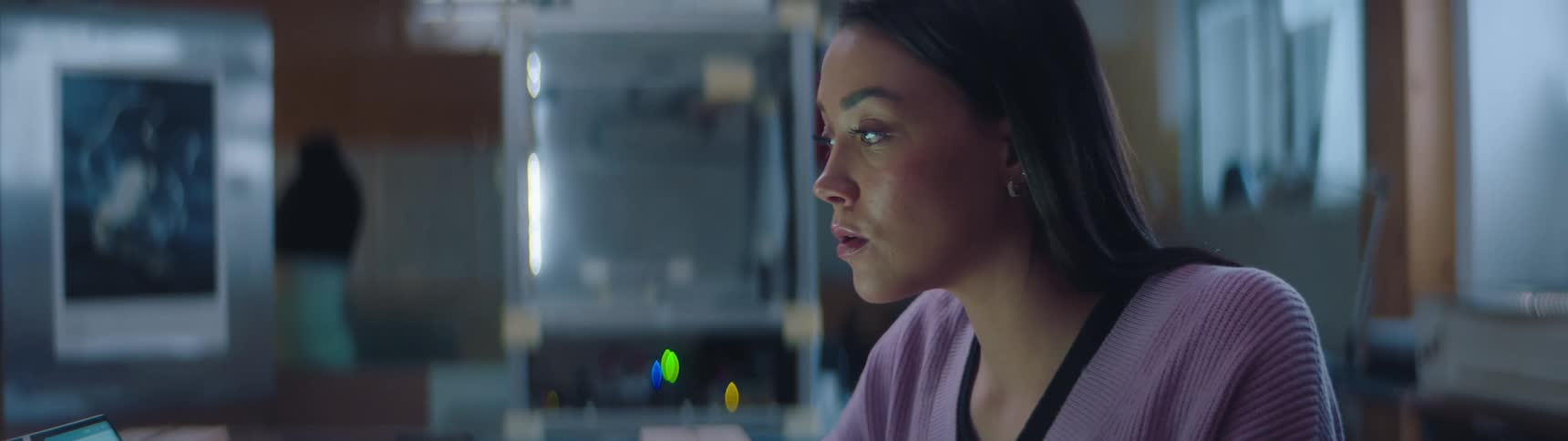 A woman in a an office looks at her laptop with a puzzled expression