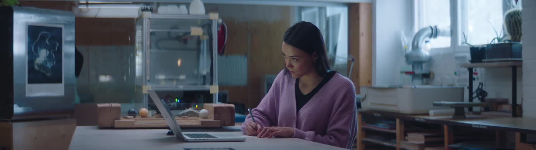 A woman is typing on a laptop indoors during the day