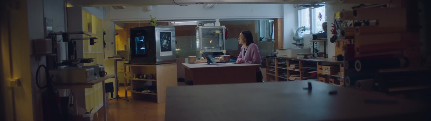 A woman is sitting by a laptop indoors during the daytime