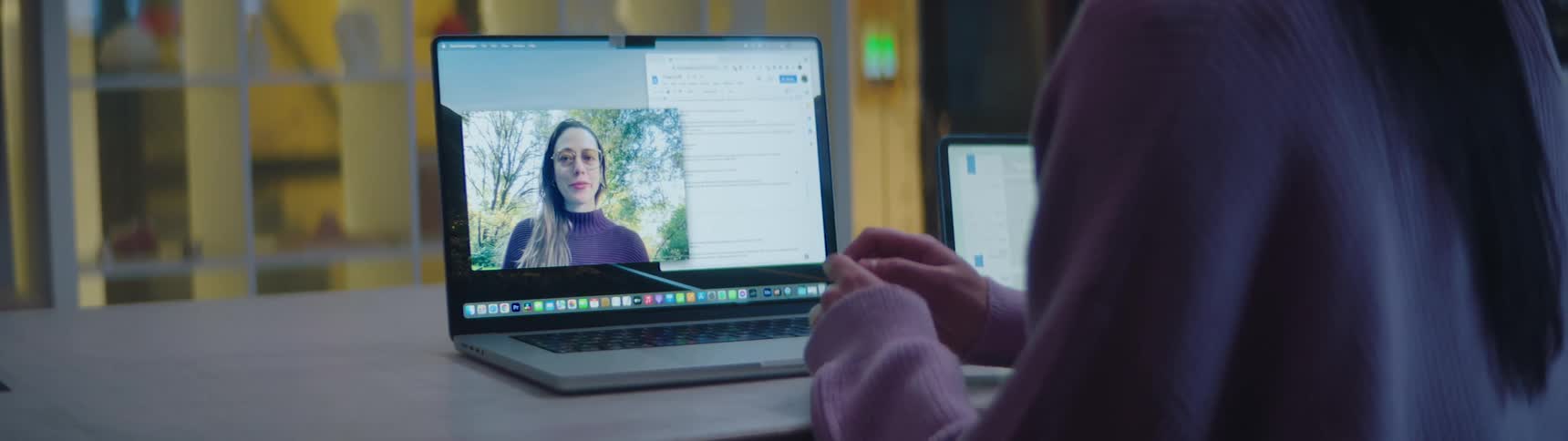 A teenage girl is sitting at a desk having a video conference with another girl on a laptop computer