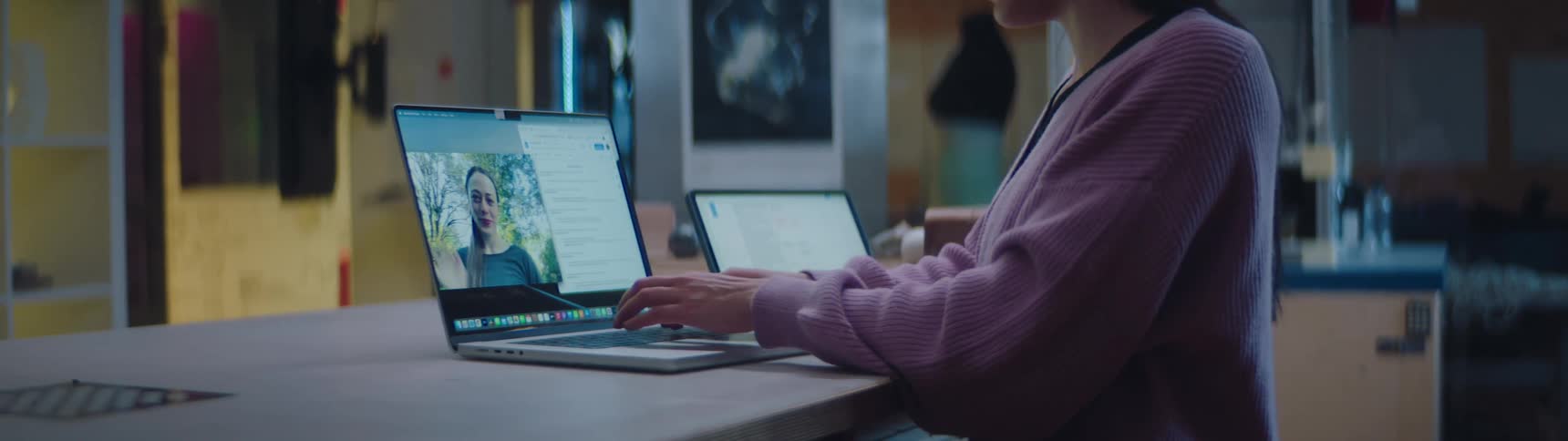 A woman waves to her counterpart on screen during a video meeting