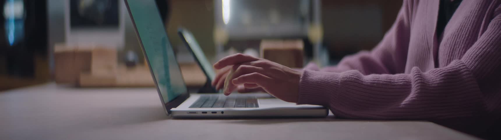 Someone is sitting at a desk typing on a laptop computer