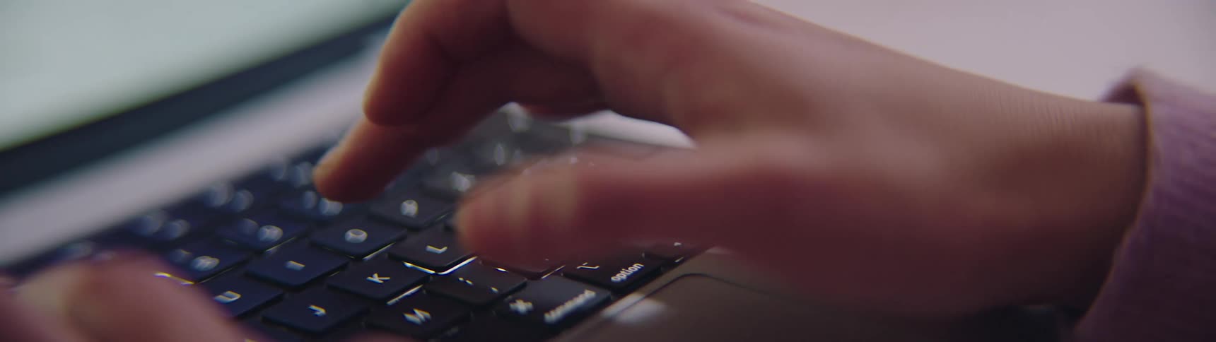 A woman is typing on a keyboard for a computer
