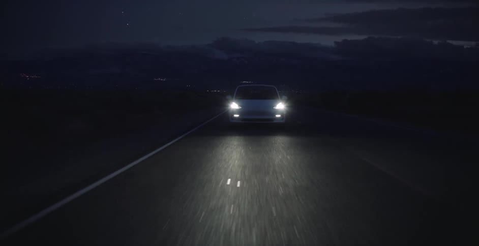 A car is driving on a road at night