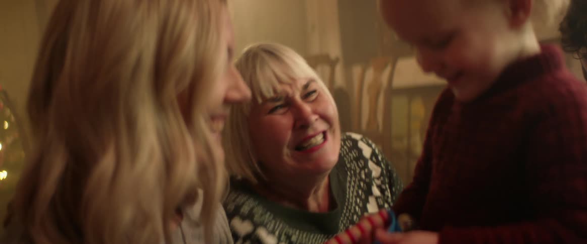 Mother and grandmother interact with boy as dad sits in background
