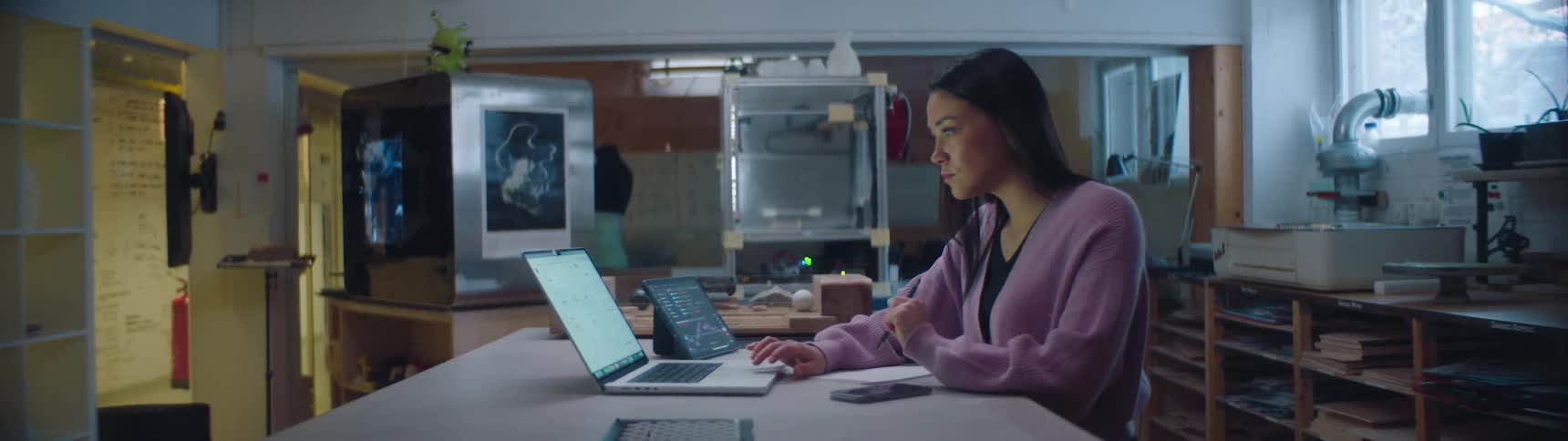 A young woman sits in an office and thinks as she looks at her computer