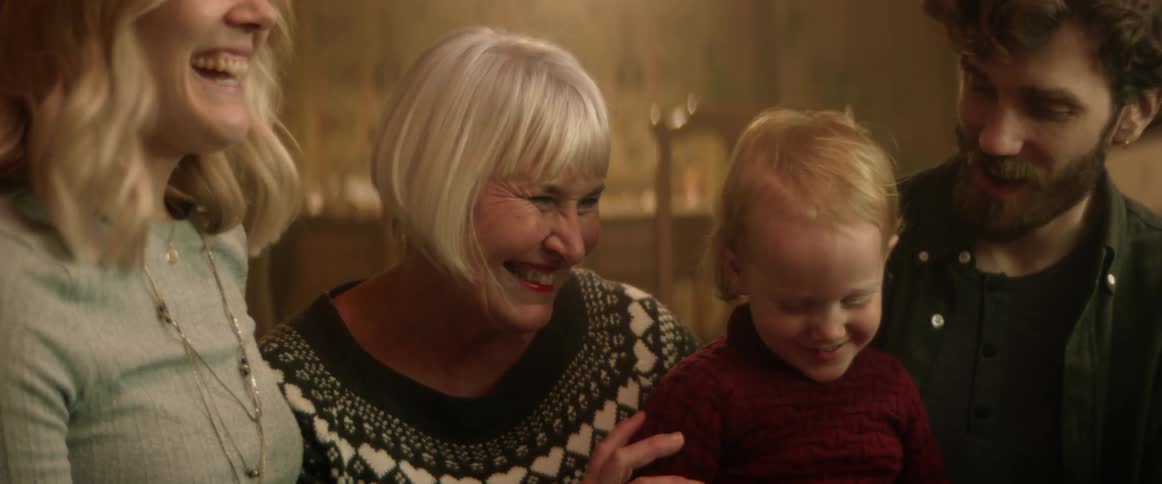 Grandmother hugging her grandson on the couch near his parents at home at christmas