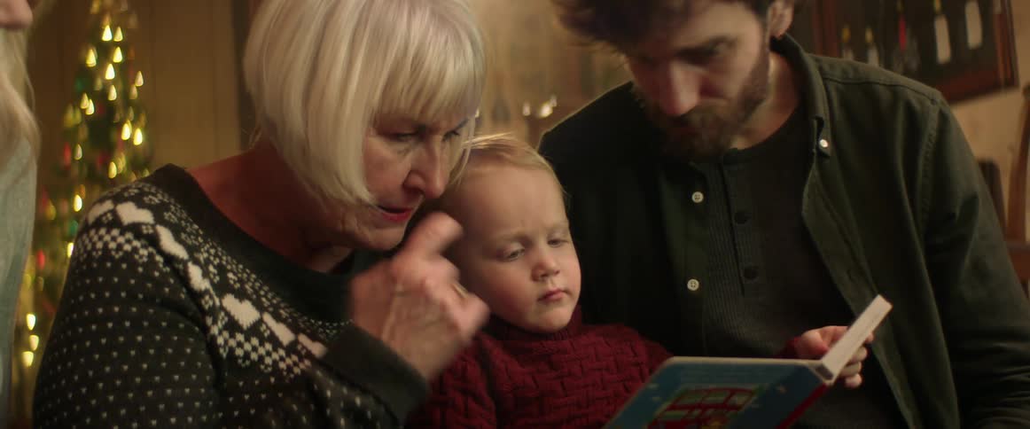 A grandmother reads a book to a child
